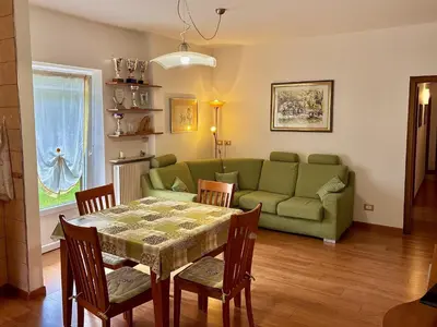 a living room with a table and a green couch at Appartamento Olimpiadi 2026 Val di Fiemme in Panchia