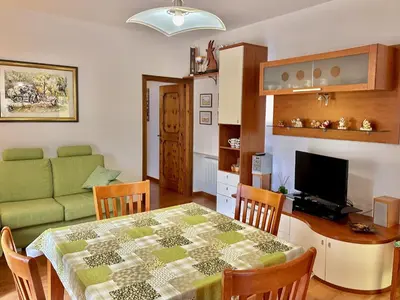 a living room with a table and a couch at Appartamento Olimpiadi 2026 Val di Fiemme in Panchia