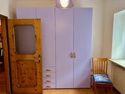 a large white closet with a door and a chair at Appartamento Olimpiadi 2026 Val di Fiemme in Panchia