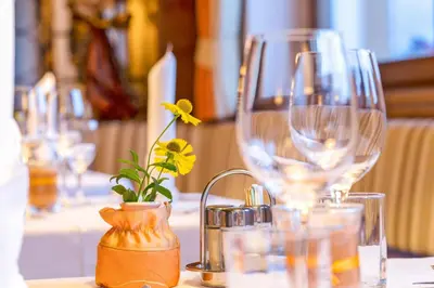 a table with wine glasses and a flower in a vase at Hotel Haus an der Luck in Barbiano