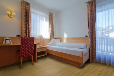 a bedroom with a bed and a desk and a chair at Hotel Haus an der Luck in Barbiano