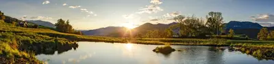 a view of a lake with the sun setting behind mountains at Hotel Haus an der Luck in Barbiano
