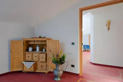 a room with a wooden cabinet and a vase with flowers at Hotel Haus an der Luck in Barbiano