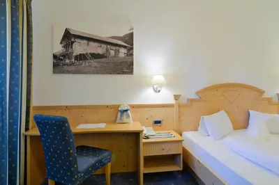 a bedroom with a bed and a desk with a chair at Hotel Haus an der Luck in Barbiano