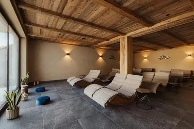 a room with chairs and tables and a wooden ceiling at Laguscei Dolomites Mountain Hotel in Arabba