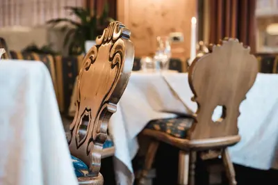 a wooden chair sitting in front of a table at Laguscei Dolomites Mountain Hotel in Arabba