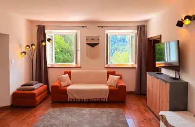 a living room with a couch and two windows at Castellino di Castello di fiemme in Castello di Fiemme