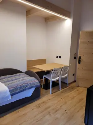 a bedroom with a bed and a table and chairs at Garni B&B Mozart Nesthouse in Canazei