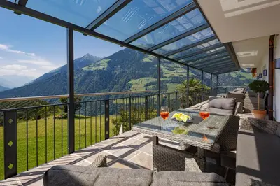 a balcony with a table and glasses of wine at Hotel Schön Aussicht in Schenna