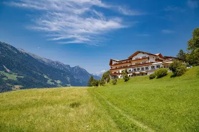 a house on a hill with a grassy field at Hotel Schön Aussicht in Schenna