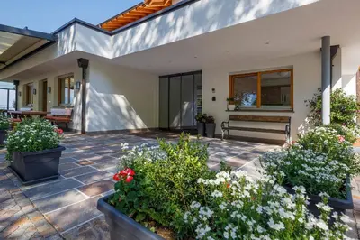 a patio with flowers and a bench on a house at Hotel Schön Aussicht in Schenna