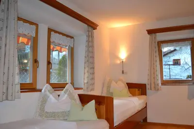 a bedroom with two beds and two windows at Ferienwohnung Pramstaller in Valdaora