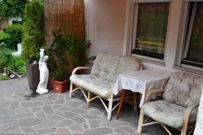 a patio with two chairs and a table and a statue at Ferienwohnung Pramstaller in Valdaora