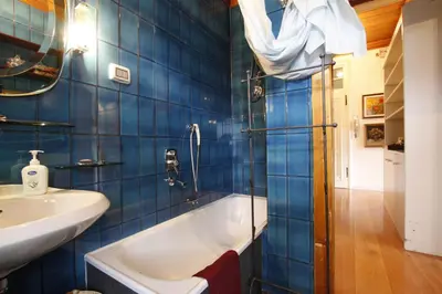 a blue tiled bathroom with a tub and a sink at Casa in Centro di Cortina D'Ampezzo in Cortina dʼAmpezzo