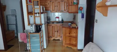 a kitchen with wooden cabinets and a white refrigerator at Casa 33 in Predazzo