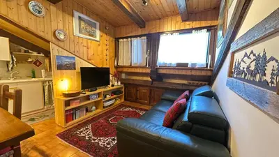 a living room with a leather couch and a television at Mansarda Chiara - locazione turistica in Gosaldo
