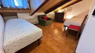 a small room with two beds and a chair at Mansarda Chiara - locazione turistica in Gosaldo