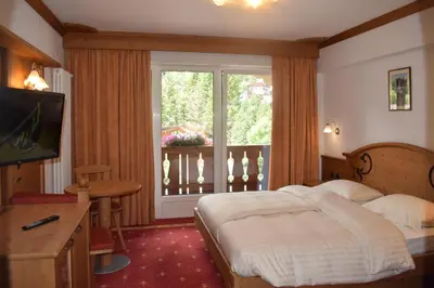 a bedroom with a bed and a large window at Hotel Crepes de Sela in Campitello di Fassa