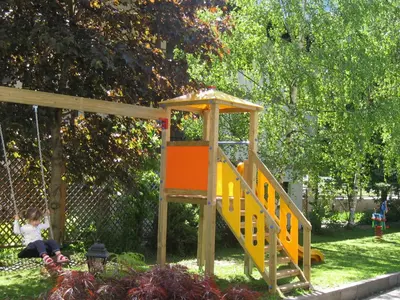 a playground with a slide in a park at Hotel Crepes de Sela in Campitello di Fassa