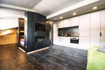 a kitchen with white cabinets and a black wall at Loft at 1236 in Ortisei