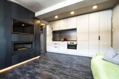 a kitchen with white cabinets and a black wall at Loft at 1236 in Ortisei