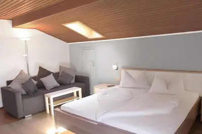 a bedroom with a white bed and a couch at Schenna Garni Eden Bed & Breakfast in Schenna