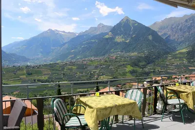 a table and chairs on a balcony overlooking a valley at Schenna Garni Eden Bed & Breakfast in Schenna