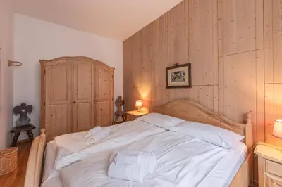 a bedroom with a large white bed with two towels at Casa Bigontina, in pieno centro a Cortina in Cortina dʼAmpezzo