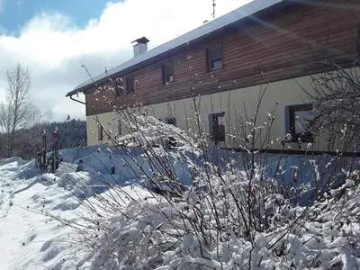 a house with snow on the side of it at Pension Ferienwohnungen Marchnerhof in Terento