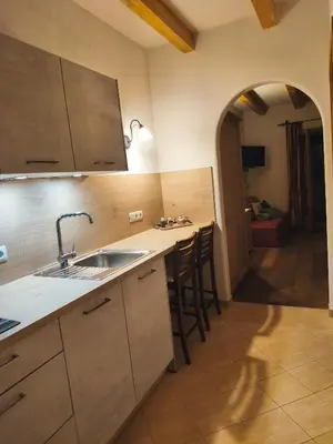 a kitchen with a sink and a counter with chairs at Pension Ferienwohnungen Marchnerhof in Terento