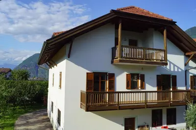 a white building with a balcony and mountains at Schabelhof in Laives