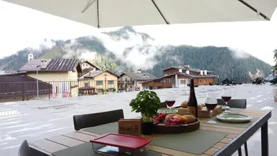 a table with a bowl of fruit and a bottle of wine at Posta Apartments in Colle Santa Lucia