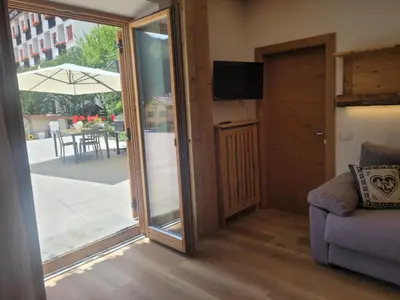 a living room with a sliding glass door and a couch at Posta Apartments in Colle Santa Lucia