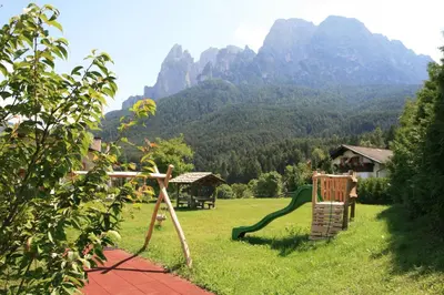 a garden with a playground with mountains in the background at Trafunshof natural living in Vols am Schlern