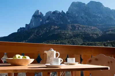 a table with a bowl of fruit on it with a mountain at Trafunshof natural living in Vols am Schlern