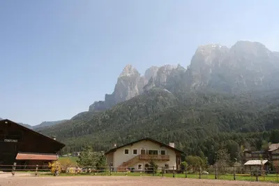 a mountain in the distance with a house in the foreground at Trafunshof natural living in Vols am Schlern