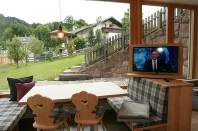 a screened in porch with a television on a table and chairs at Trafunshof natural living in Vols am Schlern