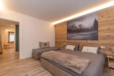 a bedroom with two beds and a large painting on the wall at Ciesa Abete Rosso in Caprile