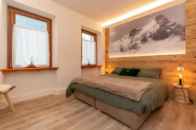 a bedroom with a bed and two windows at Ciesa Abete Rosso in Caprile