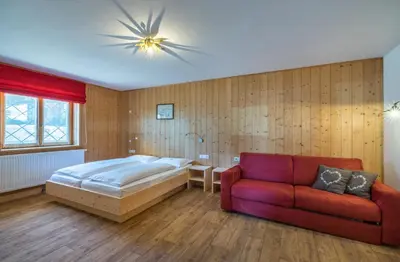 a bedroom with a bed and a couch at Berghotel Schlemmer Appartements in Plancios