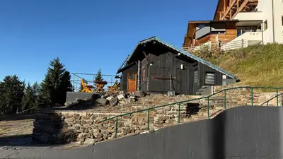 a building with a stone wall next to a house at Berghotel Schlemmer Appartements in Plancios