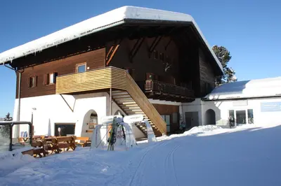 a building in the snow with skis in front of it at Berghotel Schlemmer Appartements in Plancios