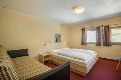 a bedroom with a bed and a couch at Berghotel Schlemmer Appartements in Plancios