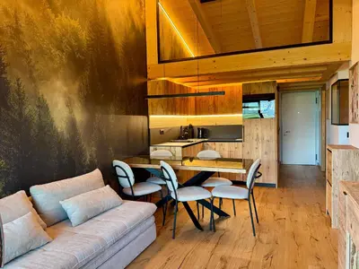 a living room with a couch and a table and chairs at Olimpo Dolomitico in Cavalese