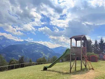 a playground with a slide on a hill with mountains at Olimpo Dolomitico in Cavalese