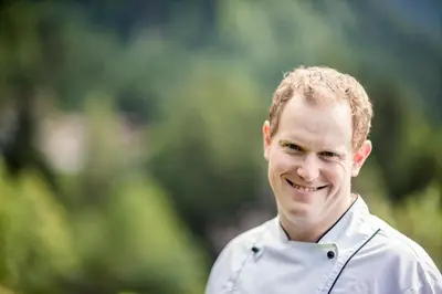 a man smiling while wearing a white shirt at Berggasthof Locanda Alpina Dorfner in Montagna