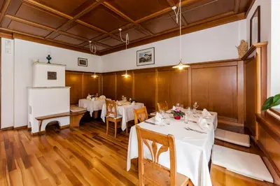 a dining room with white tables and wooden walls at Berggasthof Locanda Alpina Dorfner in Montagna