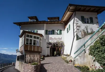 a white building with a sign on the side of it at Berggasthof Locanda Alpina Dorfner in Montagna