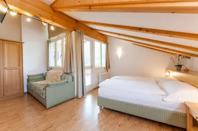 a bedroom with a bed and a chair at Berggasthof Locanda Alpina Dorfner in Montagna