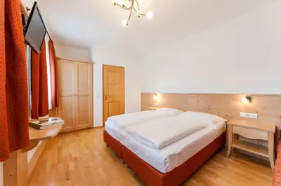 a bedroom with a bed and a desk and a tv at Berggasthof Locanda Alpina Dorfner in Montagna